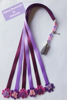 purple ribbon with flowers and tassels attached to it