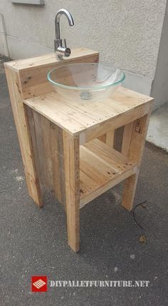 a sink made out of pallet wood with a glass bowl