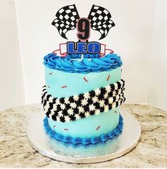 a birthday cake with blue frosting and black and white designs on it, sitting on a table