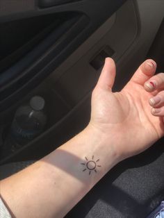 a woman's arm with a small sun tattoo on the middle of her wrist