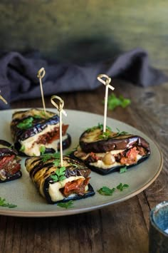 several stuffed eggplant bites on a plate with toothpicks