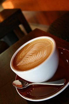 a cappuccino on a saucer with a spoon sitting on a table