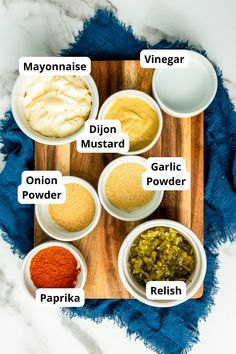 an overhead view of different spices on a cutting board with the names in their bowls