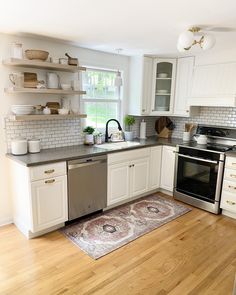 a clean kitchen with white cabinets and stainless steel stove top oven, dishwasher, sink, and microwave