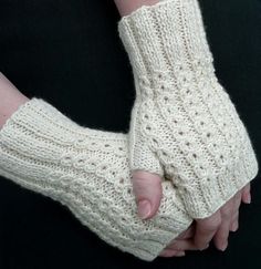 a woman wearing white knitted arm warmers and holding her hand out to the side