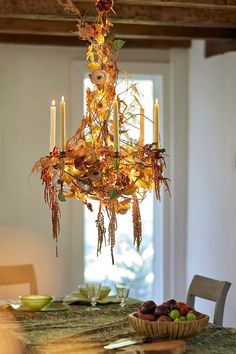 a chandelier hanging from the ceiling in a dining room with candles and fruit