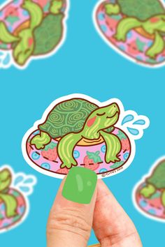 a hand holding up a sticker with a turtle on it