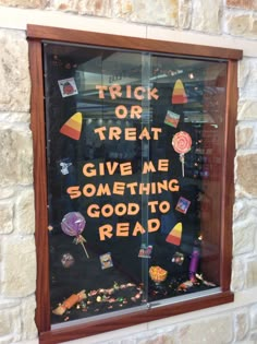 a window display with candy and candies written on the glass for trick or treat give me something good to read