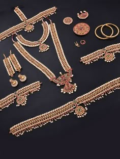 an assortment of gold jewelry including necklaces and bracelets, on a black background