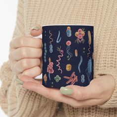 a woman is holding a coffee mug with designs on it and her hands are in the air