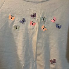 a white t - shirt with butterflies on it