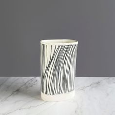 a black and white vase sitting on top of a marble countertop next to a gray wall