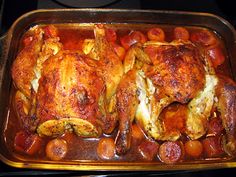 a roasting pan filled with chicken, potatoes and carrots on top of a stove