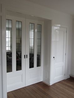 an empty room with white doors and wood floors