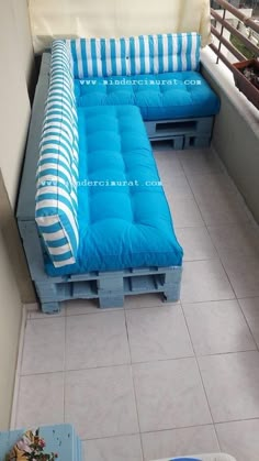 a couch made out of pallets sitting on top of a tiled floor next to a window