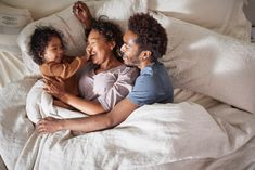 a man, woman and child laying in bed together