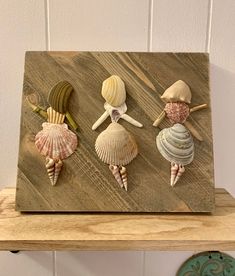 three seashells are sitting on top of a wooden shelf next to a clock