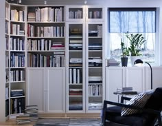 a living room filled with lots of books and furniture next to a large book shelf