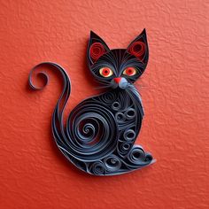 a paper cut cat sitting on top of a red wall