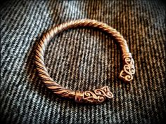 a close up of a gold bracelet on a gray cloth with the word love written in cursive writing