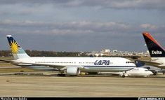 two airplanes are parked on the tarmac at an airport, one is blue and white