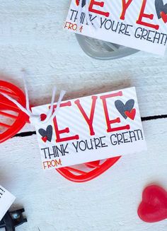 two valentine's day cards with red and black hearts tied to them on a white surface