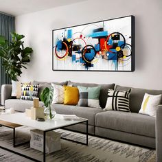 a living room filled with furniture and a painting hanging on the wall above it's coffee table