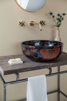 a bowl shaped sink sits on top of a wooden table in front of a mirror