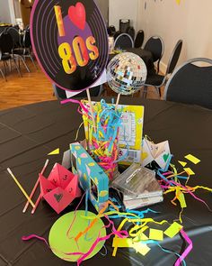 a table topped with lots of party supplies and balloons in the shape of 80s's