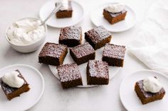 several pieces of brownie on plates with whipped cream in the bowl next to them