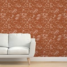 a white couch sitting in front of a wall with an orange and white pattern on it