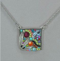 a square necklace with colorful beads and leaves on the front, hanging from a silver chain