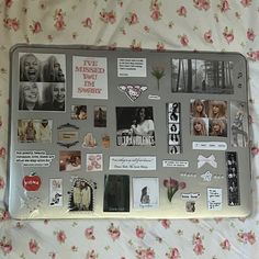 a laptop covered in pictures and magnets sitting on a floral bed sheet with pink flowers