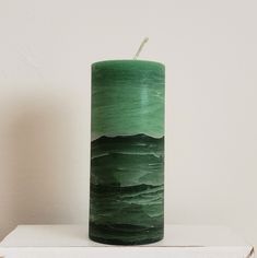 a green candle sitting on top of a white shelf