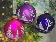 three christmas ornaments hanging from a tree branch