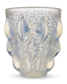 a clear glass vase with flowers and leaves on the rim, set against a white background