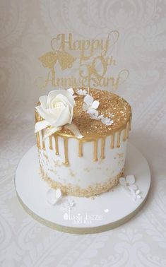 a white cake with gold frosting and a flower on top