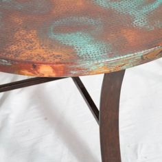 an old metal table with rusted paint on it's top and wood legs