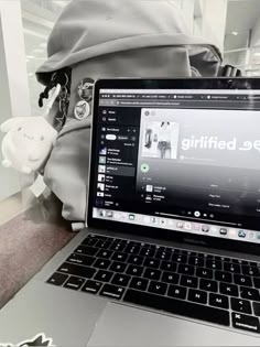 an open laptop computer sitting on top of a wooden desk next to a stuffed animal