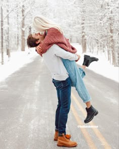 a man and woman kissing in the middle of an empty road with snow on the ground