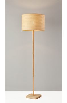 a wooden floor lamp with a beige shade on the base and a white drum light behind it