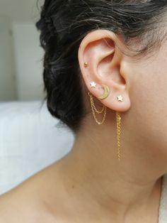 a close up of a person with ear piercings on their ears and wearing gold chains