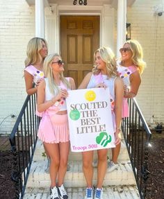 three girls in pink dresses holding a sign on the front steps of a white house