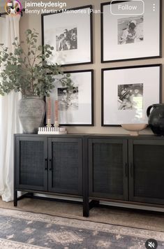 a living room with pictures on the wall and plants in vases next to it