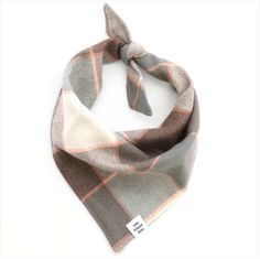 a gray and orange plaid scarf with a white tag hanging from the side on a white background