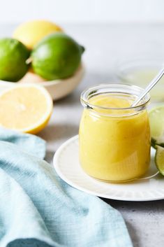 a glass jar filled with yellow liquid next to sliced limes on a white plate