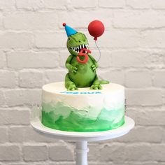 a birthday cake with a green and white frosting monster holding a red balloon on top