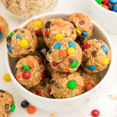 a white bowl filled with peanut butter m & m cookie energy bites on top of a table