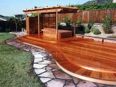 a wooden gazebo sitting on top of a lush green field next to a stone walkway