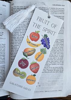 an open bible with fruit of the spirit bookmark and tassels on it